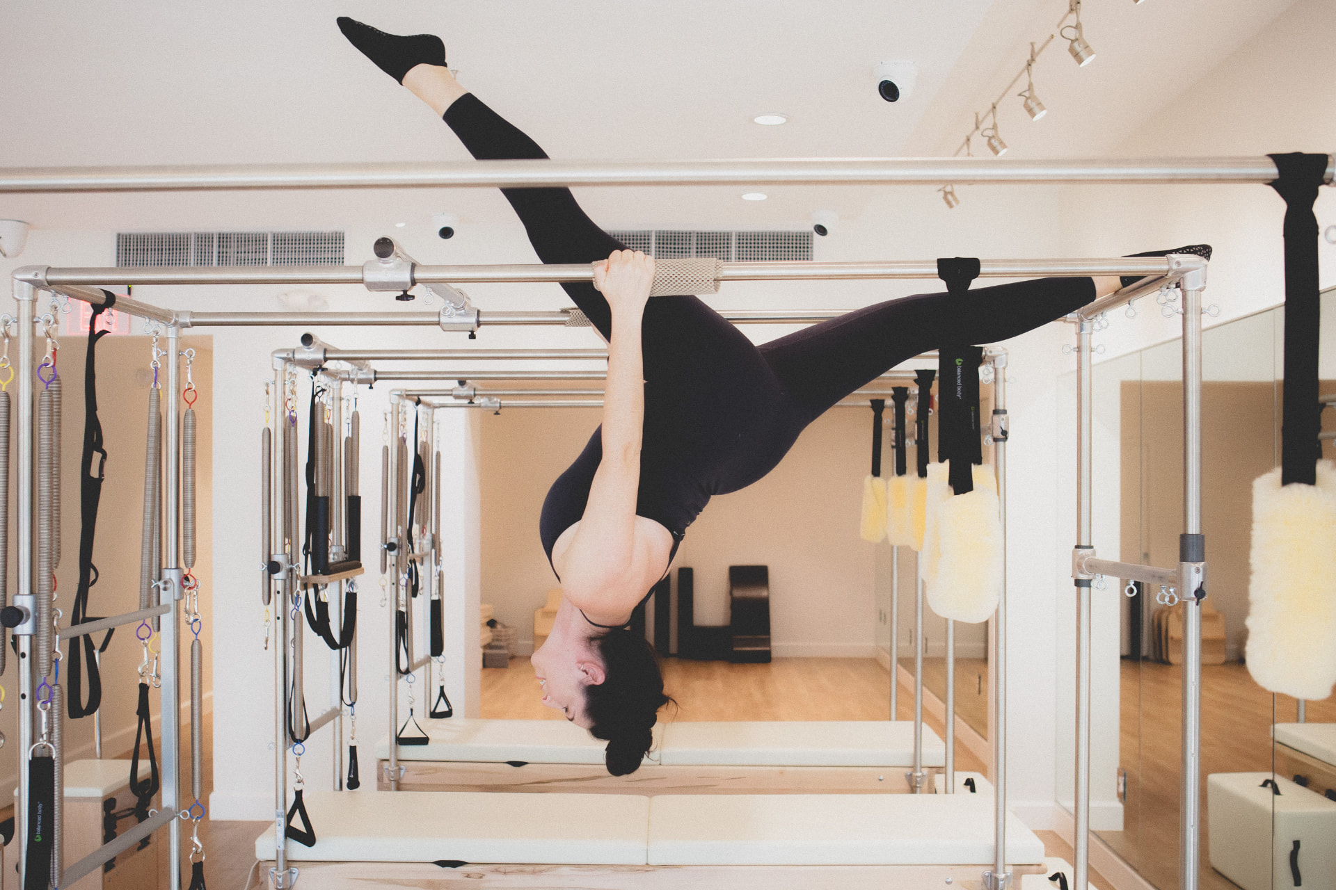 A woman practicing Classical Pilates on a reformer in a sunlit studio